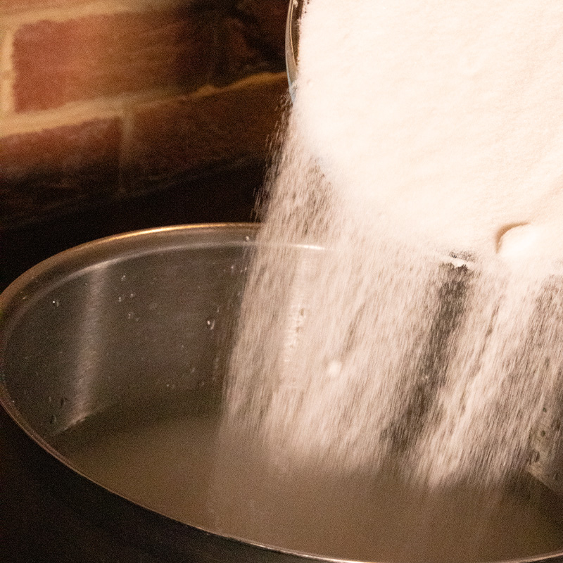 Sugar being added to a pan of water