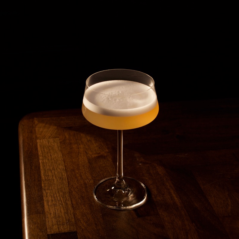 Clarified Mango, Passion Fruit Sours Cocktail Complete Clarified Mango, Passion Fruit Sours Cocktail served in a glass sat on the side of the bar