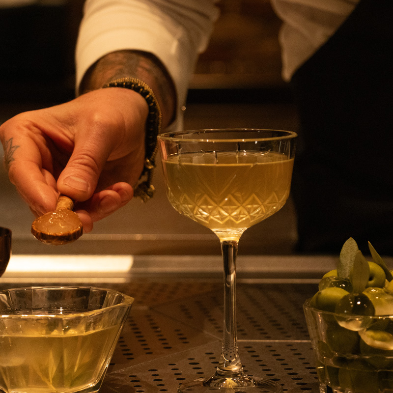 The Nocellara Del Belice Olive Martini being garnished with the reverse-spherified olive.
