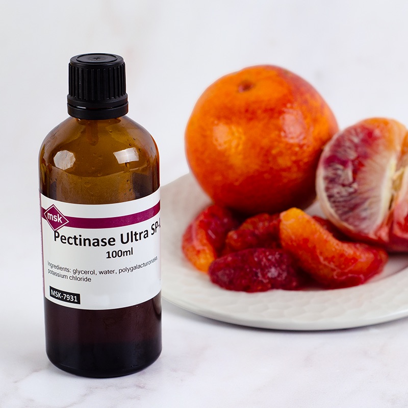A bottle of MSK Pectinase Ultra SP-L alongside a enzyme peeled blood orange